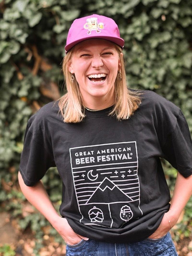 A laughing woman wears the official Great American Beer Festival t-shirt and Beer Dude cap made by B Fresh Gear.