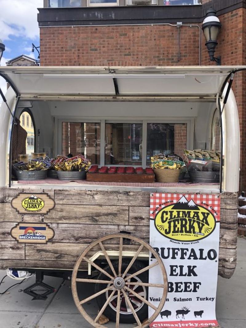Climax Jerky's branded wooden retail cart on a Breckenridge, Colorado street, stocked with packaged jerky.