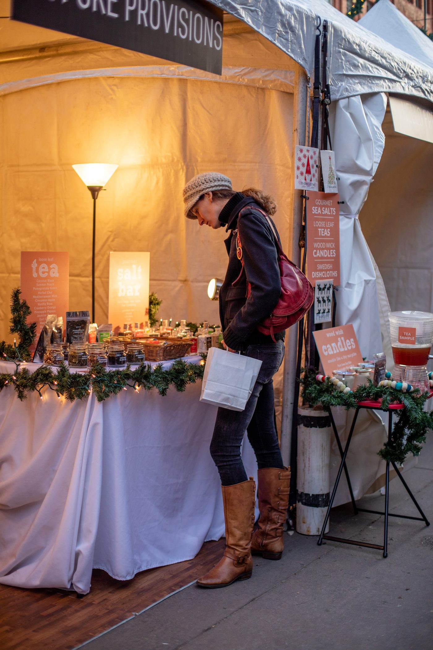 A maker booth decorated with garland and string lights at Holiday BAZAAR